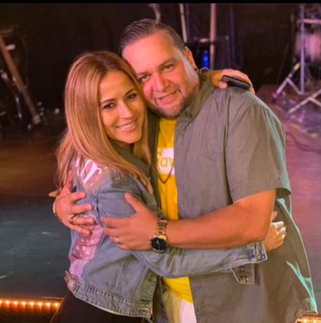 Jackie Guerrido in a blue denim jacket hugging her late brother in grey shirt.
